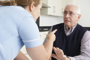 nursing aid pointing finger and yelling at elderly man