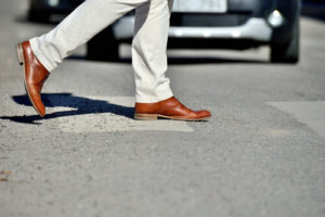 pedestrian using crosswalk with cars in the background