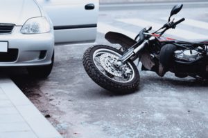 Edmond Motorcycle Accident scene with motorcycle lying on side next to parked car