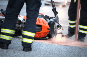 fire fighters looking at motorcycle accident with gasoline spill 