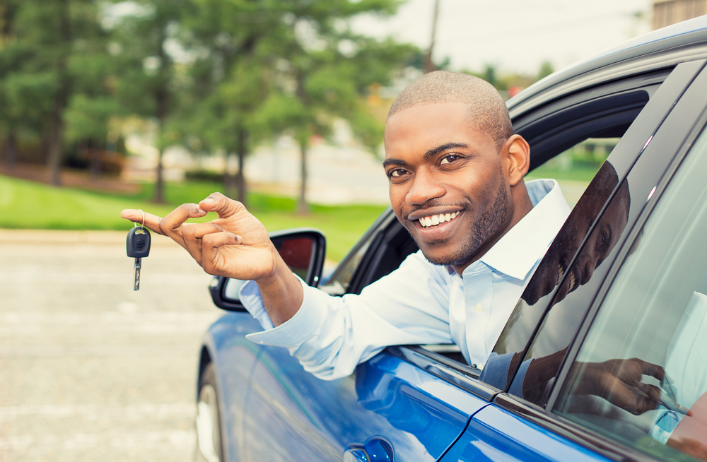 person with key dangling from finger hanging out of car window