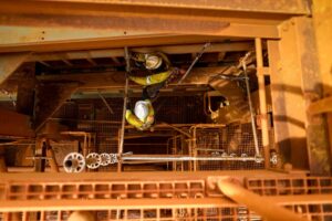 aerial view of a drill rig with two workers below installing piping